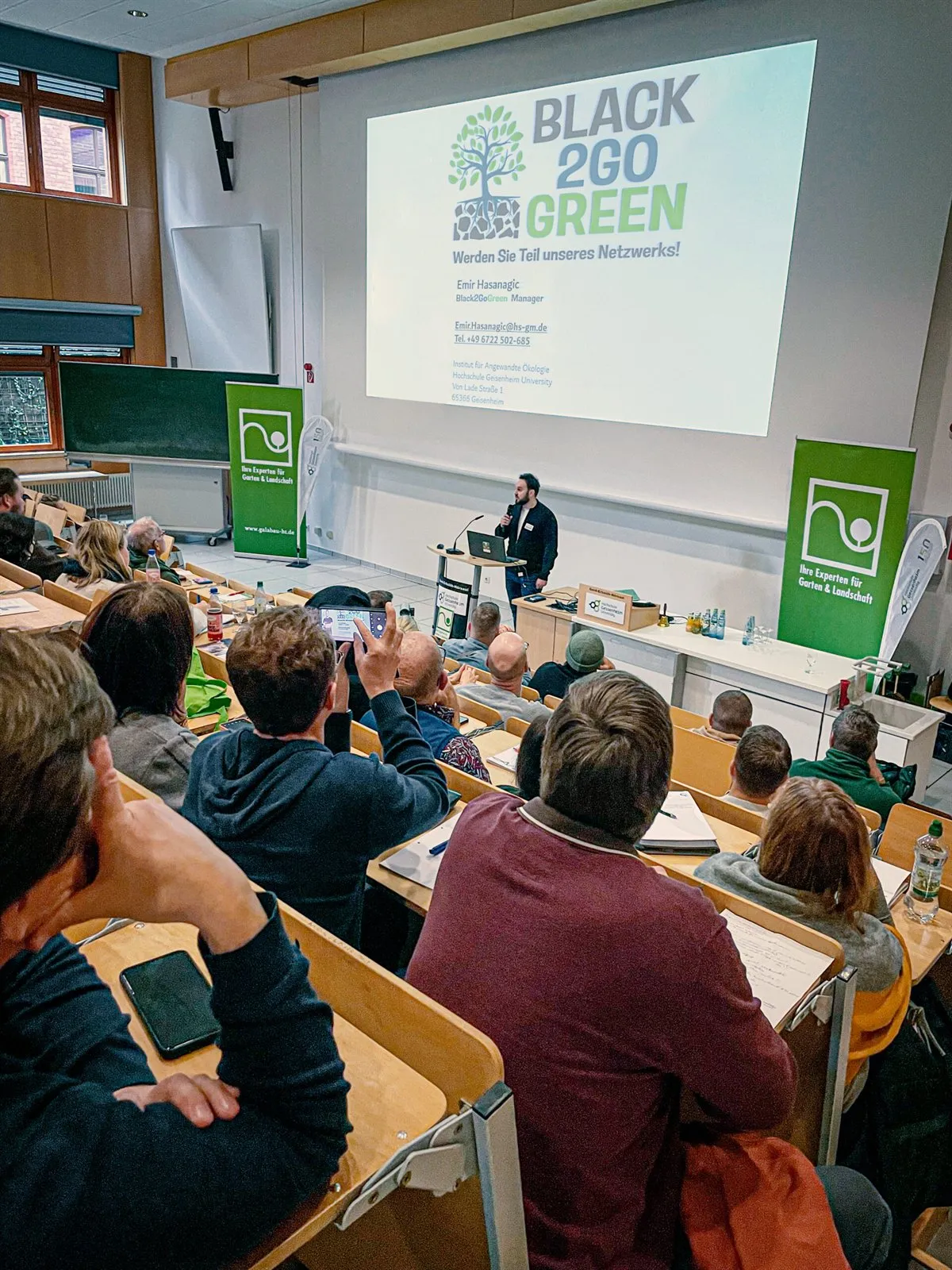 Blick über das Publikum auf die Leinwand mit dem Black2GoGreen-Logo