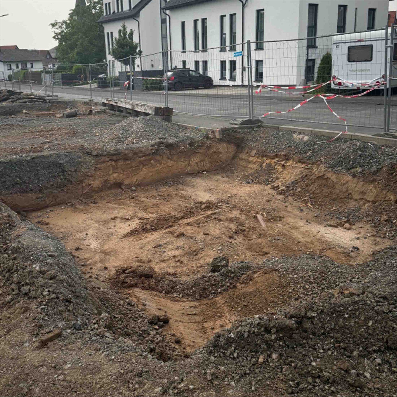 Großflächig ausgehobene Baugrube vor Wohnhäusern – Bau des Reallabors am Bürgerhaus Wißmar