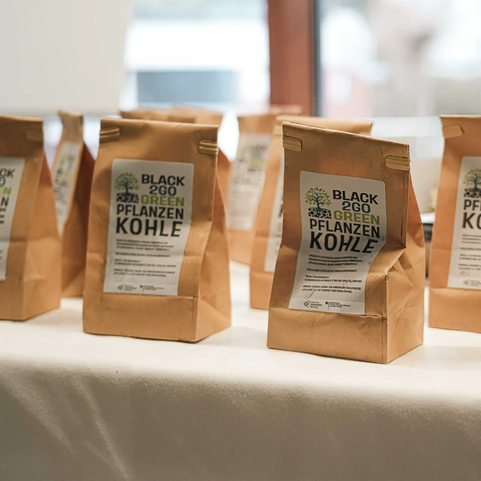 Papiertüten mit Black2GoGreen-Pflanzenkohle auf einem Tisch
