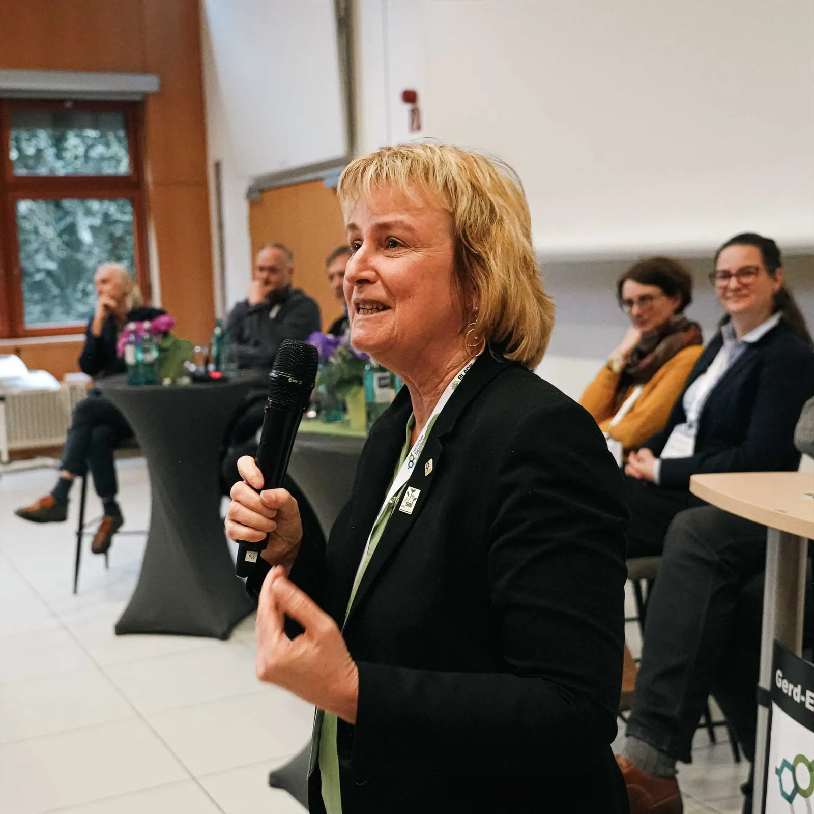 Teilnehmerin spricht mit Mikrofon im Hörsaal