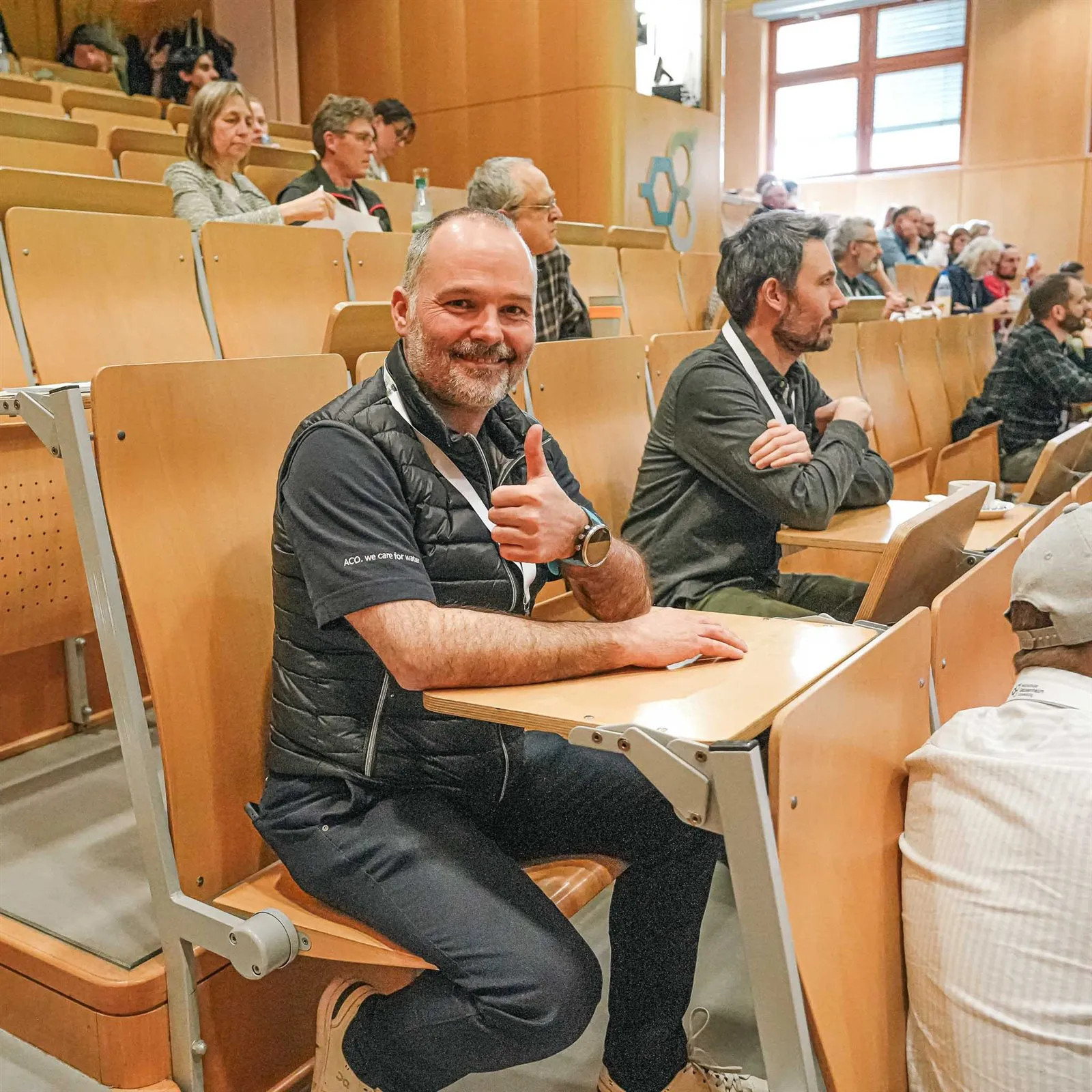 Teilnehmer lacht in einer Sitzreihe des Hörsaals
