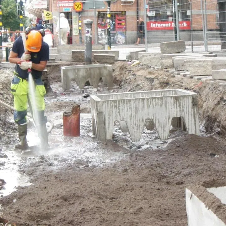 Arbeiter spült mit einem Wasserschlauch Substrat in den Schotter