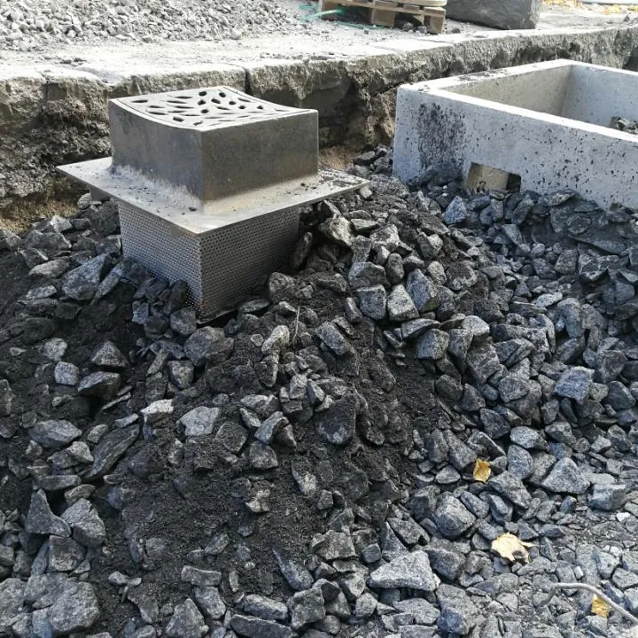 Einbau von Pflanzenkohle-Schotter um einen Belüftungsbrunnen und eine Betoneinfassung