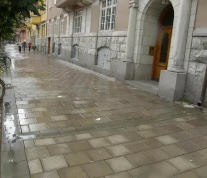 Gehweg an einer Hausfassade während eines Regens