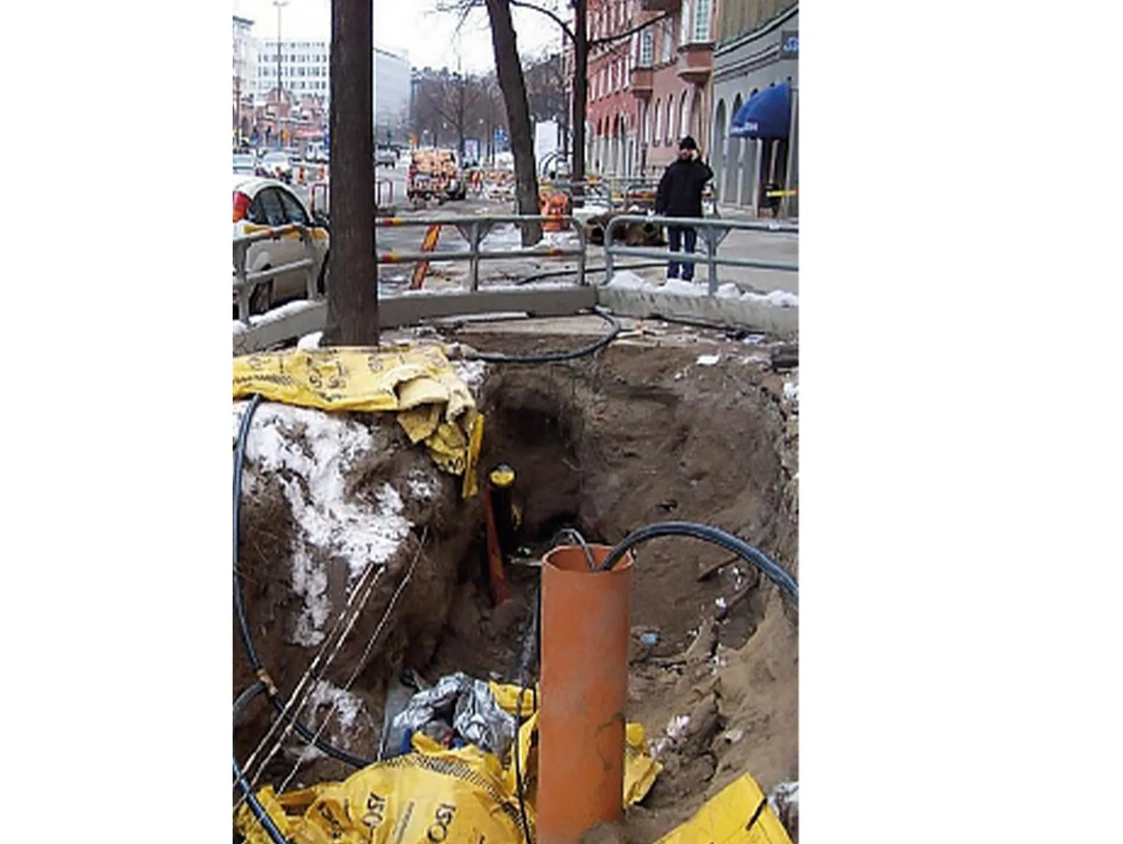 Baugrube mit Leitungsrohren direkt neben einem Baum