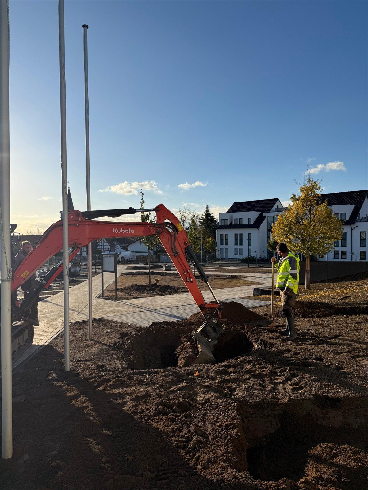 Bagger hebt eine Baumgrube am Bürgerhaus Wißmar aus, im Hintergrund Wohnhäuser