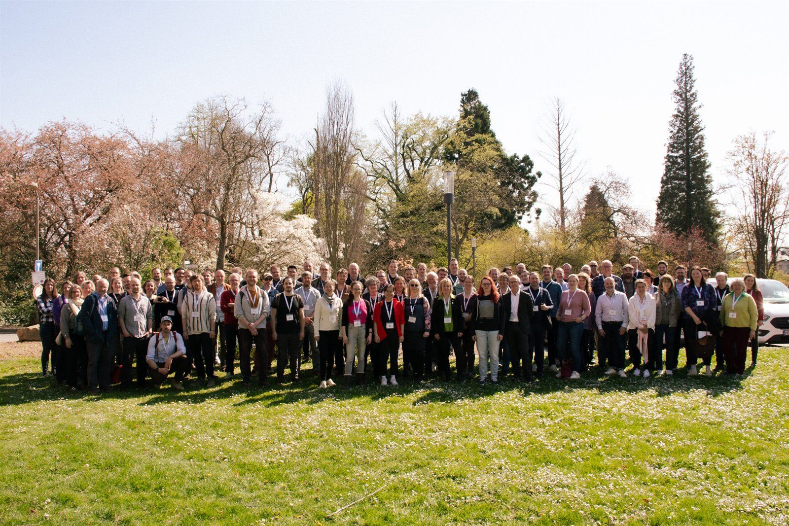 Gruppenfoto der Tagungsteilnehmenden auf einer Wiese im Park der Hochschule Geisenheim, im Hintergrund blühende Bäume