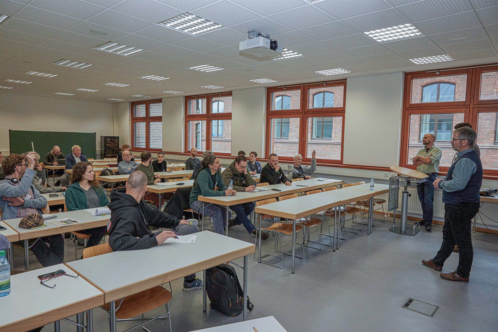 Teilnehmende an Tischen in einem Seminarraum